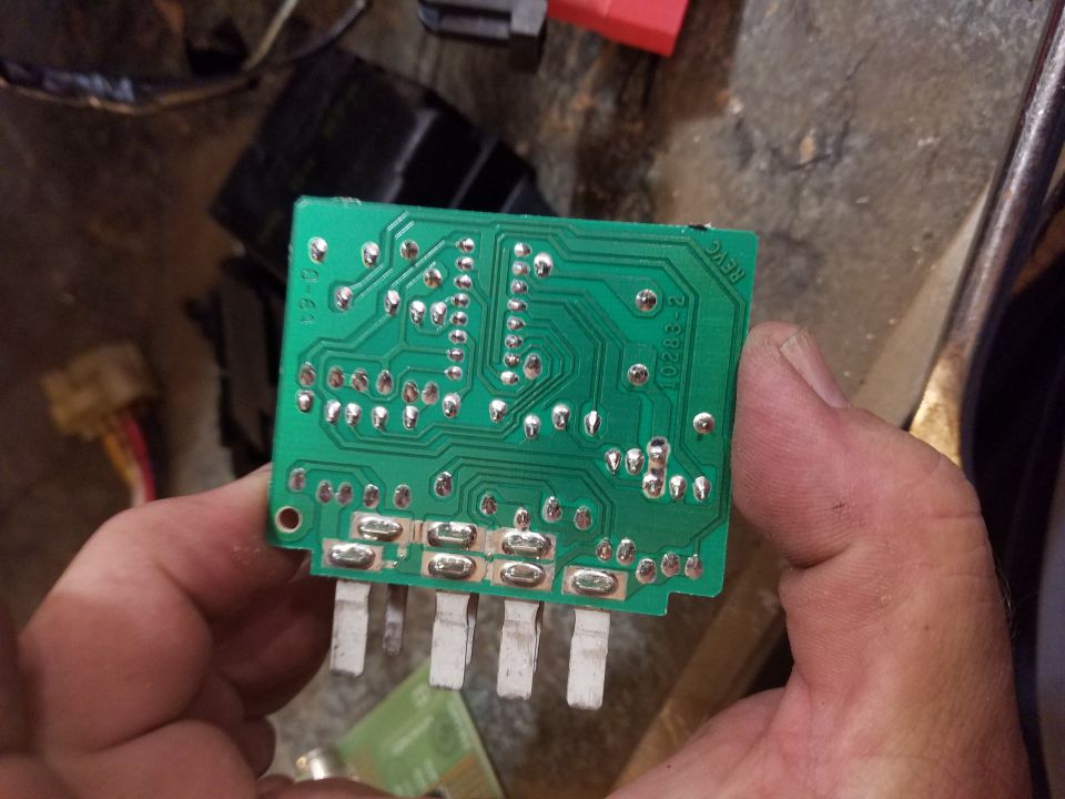 Close-up of a green circuit board with silver solder points and pins. Text reads 'REVC P-38201'