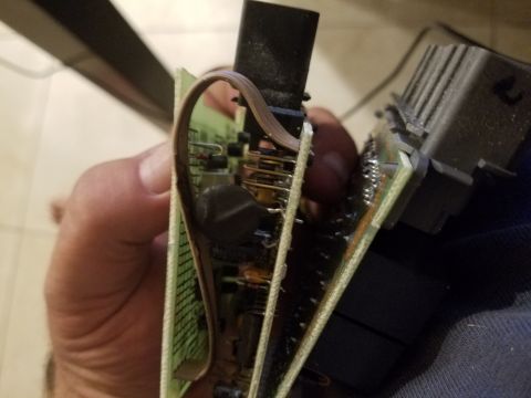 1994 Ford Bronco - A hand holds an electronic control module, revealing its internal circuitry and connectors.