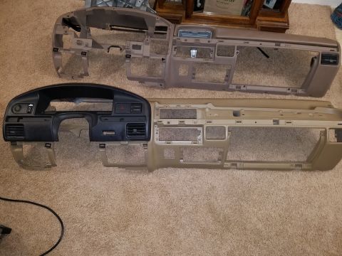 1994 Ford Bronco - Two vehicle dashboards are laid out on a carpeted floor, likely for repair or replacement.