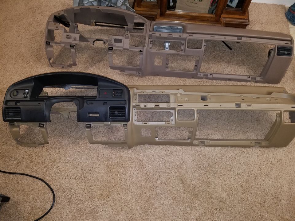Two disassembled vehicle dashboards, one black and tan, one tan