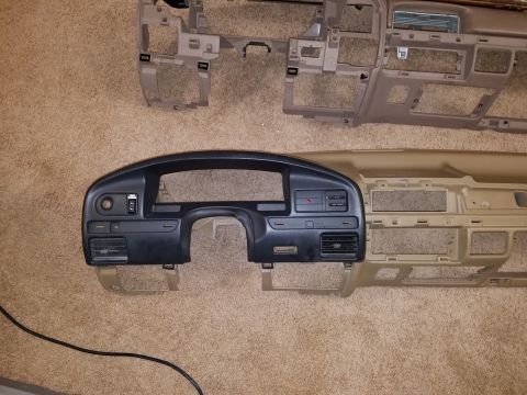 1994 Ford Bronco - Photograph of a disassembled dashboard bezel and trim panels placed on carpet.