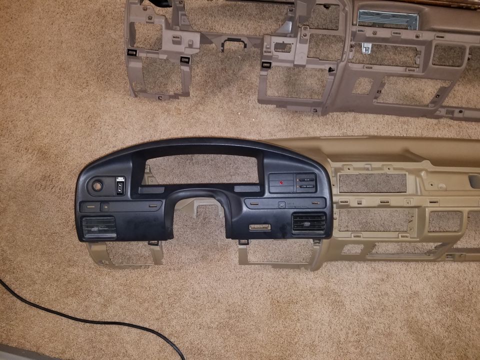 Photo of a vehicle dashboard instrument bezel and dash panels laid on carpet