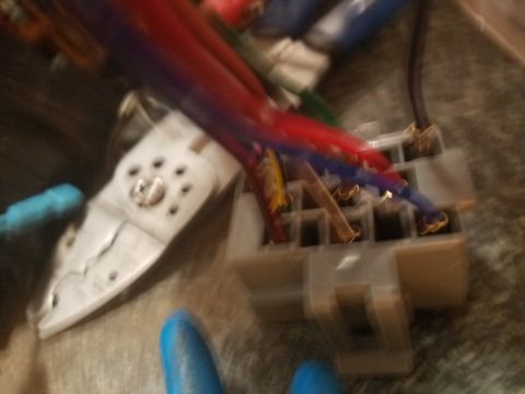 1994 Ford Bronco - Out-of-focus photograph of an electrical connector and crimping tool during wiring work.