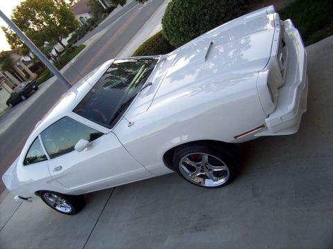 1978 Ford Mustang II - White 1978 Ford Mustang II coupe parked on a driveway with a dark car in the background.