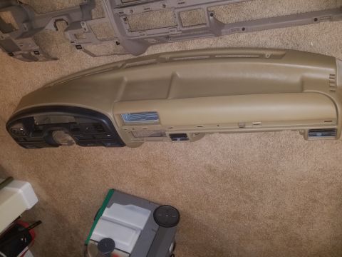 1994 Ford Bronco - Photograph of a tan automotive dashboard pad on carpet, not a technical document.