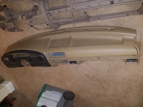 1994 Ford Bronco - Photograph of a tan automotive dashboard assembly laid on carpet, not a technical document.