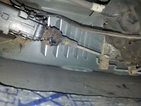 1994 Ford Bronco - Photograph of a corroded automotive steering/suspension component under a vehicle, not a technical document.