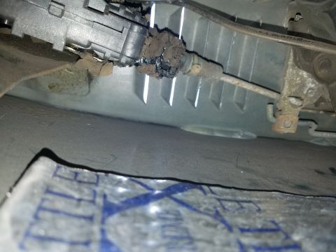 1994 Ford Bronco - Photograph of a corroded automotive steering/column component under a vehicle, not a technical document.