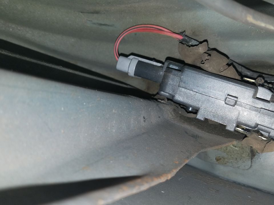 Photo of an electrical switch or actuator with a red wire under the dash