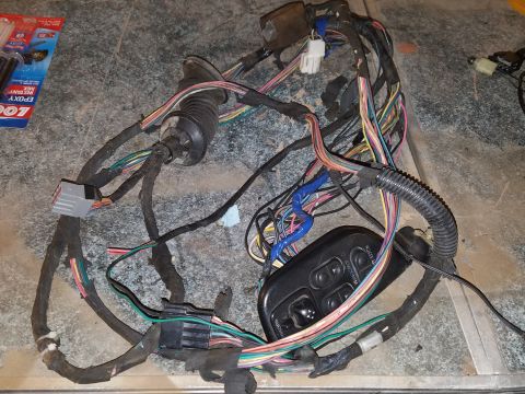 1994 Ford Bronco - Photograph of an automotive door wiring harness and master power-window switch on a table, not a document.