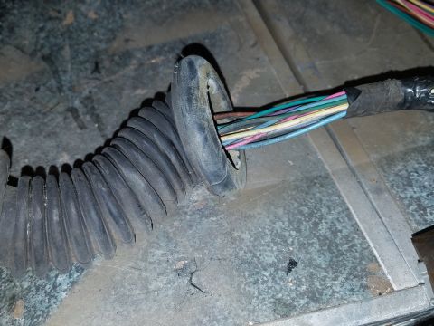1994 Ford Bronco - Photograph of an automotive wiring harness routed through a firewall grommet, not a diagram.