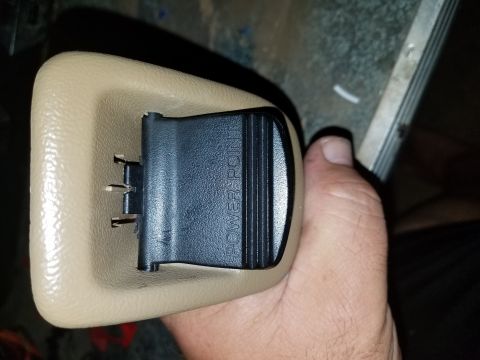 1994 Ford Bronco - Photograph of a hand-held 12V power-point socket in a tan trim bezel, not a document.