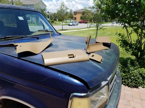 1994 Ford Bronco - Photograph of tan dash trim pieces on a truck hood, not a technical document.