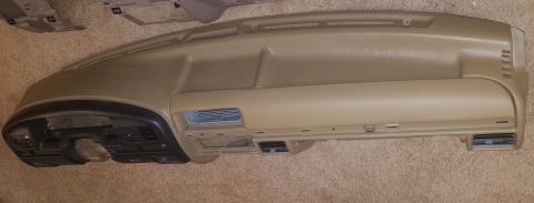 1994 Ford Bronco - Photograph of a complete tan dashboard assembly on the floor, not a technical document.