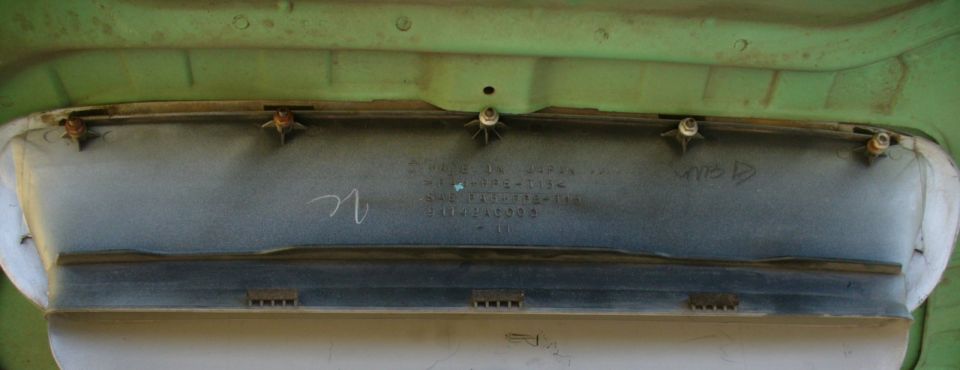 Underside of a sheet metal trunk lid or panel with mounting studs and stamped part markings