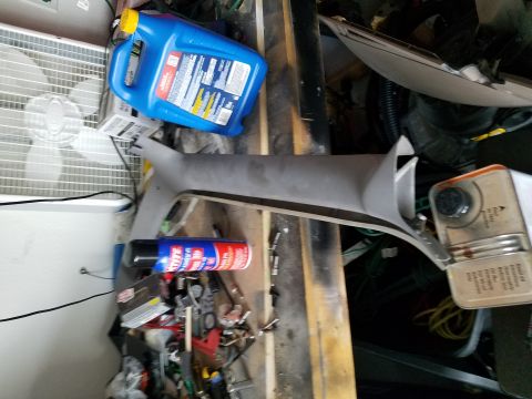 1994 Ford Bronco - Photograph of a vehicle interior pillar trim panel on a workbench among shop supplies, not a document.