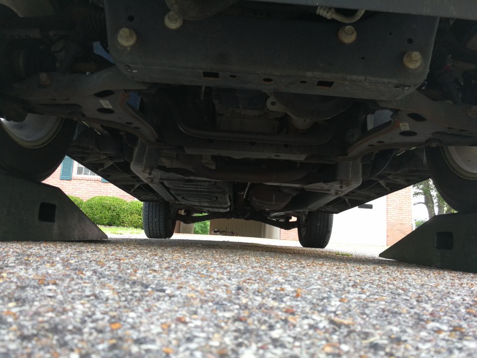 Underside of a vehicle on ramps, showing suspension and exhaust.