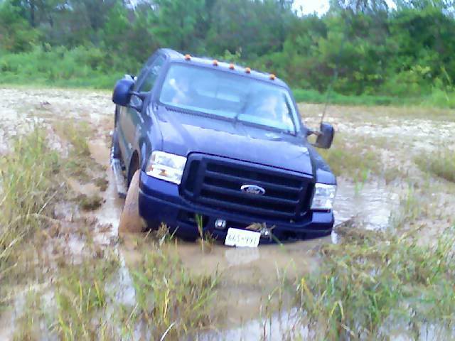 Blue Ford truck stuck in mud, front grille visible