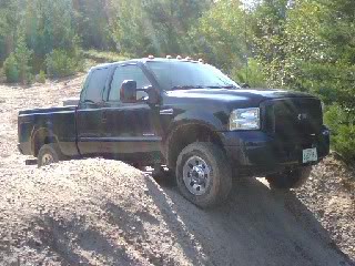 1989 Ford Bronco - A black Ford F-Series truck is shown driving off-road on a dirt mound.