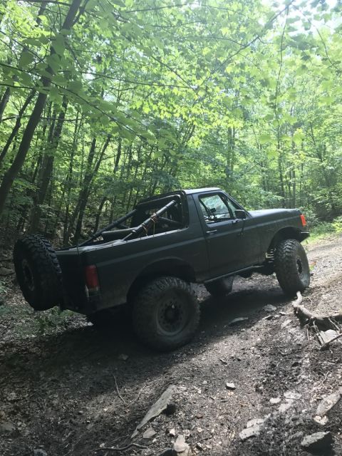 1989 Ford Bronco - Modified 1989 Ford Bronco navigating a dirt trail in a wooded area.