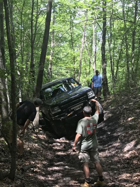 1989 Ford Bronco - A 1989 Ford Bronco attempts to climb a difficult off-road trail surrounded by trees.