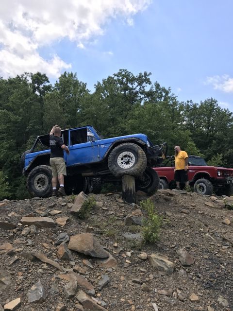 1989 Ford Bronco - A blue 1978 Ford Bronco navigates a challenging off-road course with another Bronco visible in the background.