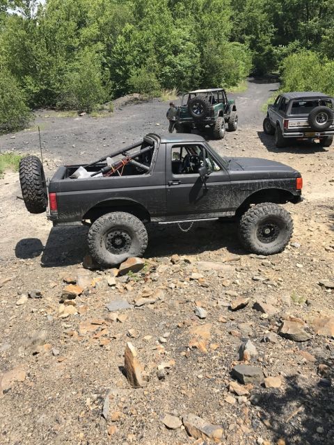 1989 Ford Bronco - Modified 1989 Ford Bronco on a trail with other off-road vehicles in the background.
