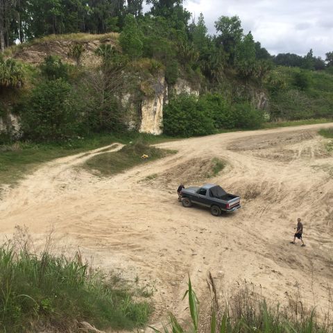 1989 Ford Bronco - 1989 Ford Bronco navigating a dirt path in a rocky, wooded area.
