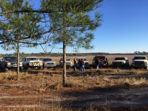 1989 Ford Bronco - A group of SUVs and trucks are parked in an open field on a sunny day.