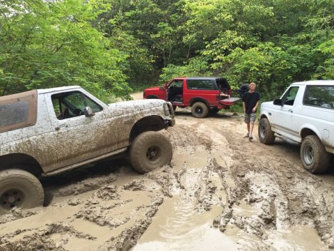 1989 Ford Bronco - Three Ford Broncos navigate a muddy trail, with one vehicle deeply mired in the mire.