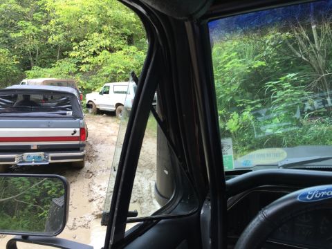 1989 Ford Bronco - A white 1989 Ford Bronco is parked on a muddy trail, viewed from the interior of another vehicle.