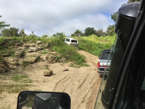 1989 Ford Bronco - Two SUVs navigate a rocky, dirt path under a cloudy sky.
