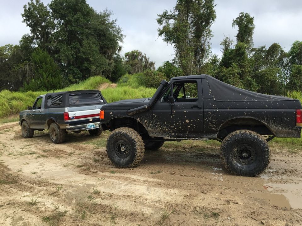 1989 Ford Bronco and another Ford Bronco on a muddy trail