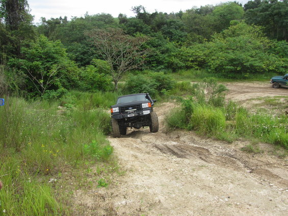 Black SUV with a winch and snorkel driving on a dirt path, trees and foliage in the background