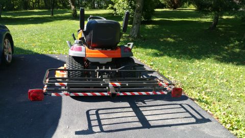 2007 Subaru Impreza - A riding lawn mower is parked on a driveway, equipped with a cargo rack and trailer hitch attachment.