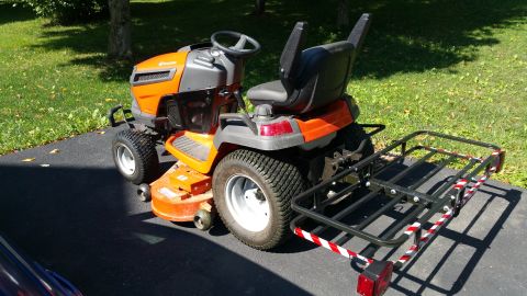 2007 Subaru Impreza - Riding lawn mower with a cargo carrier is parked on an asphalt driveway.
