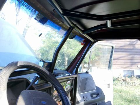 1989 Ford Bronco - The interior of a vehicle is shown, a roll cage structure and a view through the windshield.