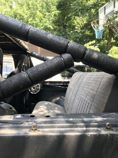 1989 Ford Bronco - Roll cage and seats inside a vehicle, with a steering wheel visible.