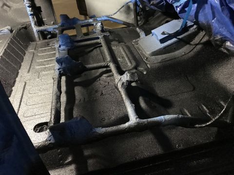 1989 Ford Bronco - Undercarriage of a vehicle being treated with protective coating during restoration.