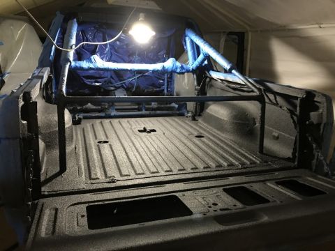 1989 Ford Bronco - The interior of a truck bed is shown, a roll cage and freshly applied spray-on liner.