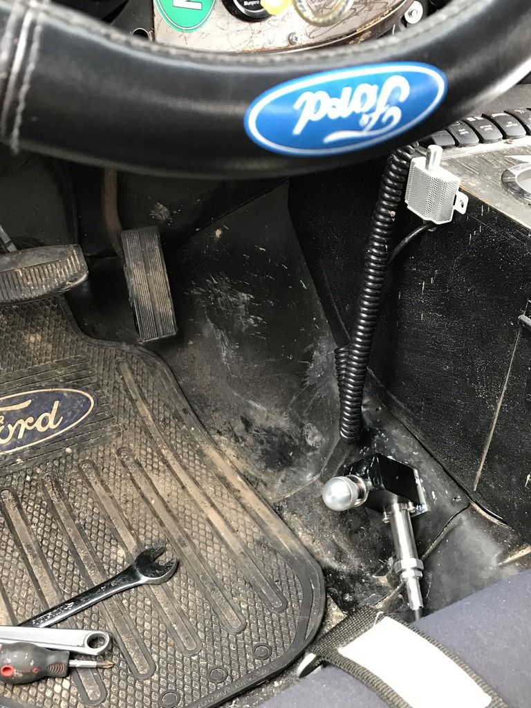 Interior view of a vehicle showing a Ford steering wheel and floor mat