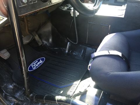 1989 Ford Bronco - The interior of a vehicle shows a Ford branded floor mat and a racing seat.