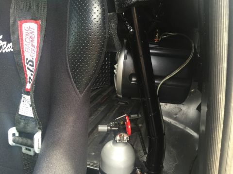 1989 Ford Bronco - Close-up view of a racing seat and a nitrous bottle mounted inside a vehicle's interior.