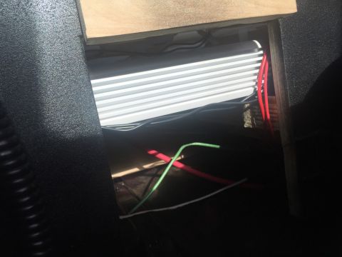 1989 Ford Bronco - A car amplifier and wiring are visible within a dark interior compartment, with a wooden panel above.