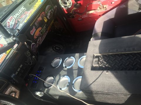 1989 Ford Bronco - The vehicle's interior features a custom console with speakers and switches, along with numerous stickers on the dashboard.