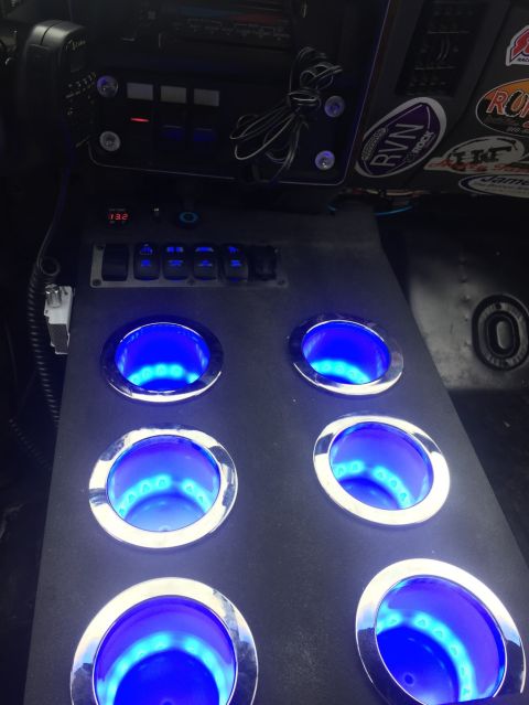 1989 Ford Bronco - The interior of a vehicle shows a custom console with six blue-lit cup holders and numerous switches.