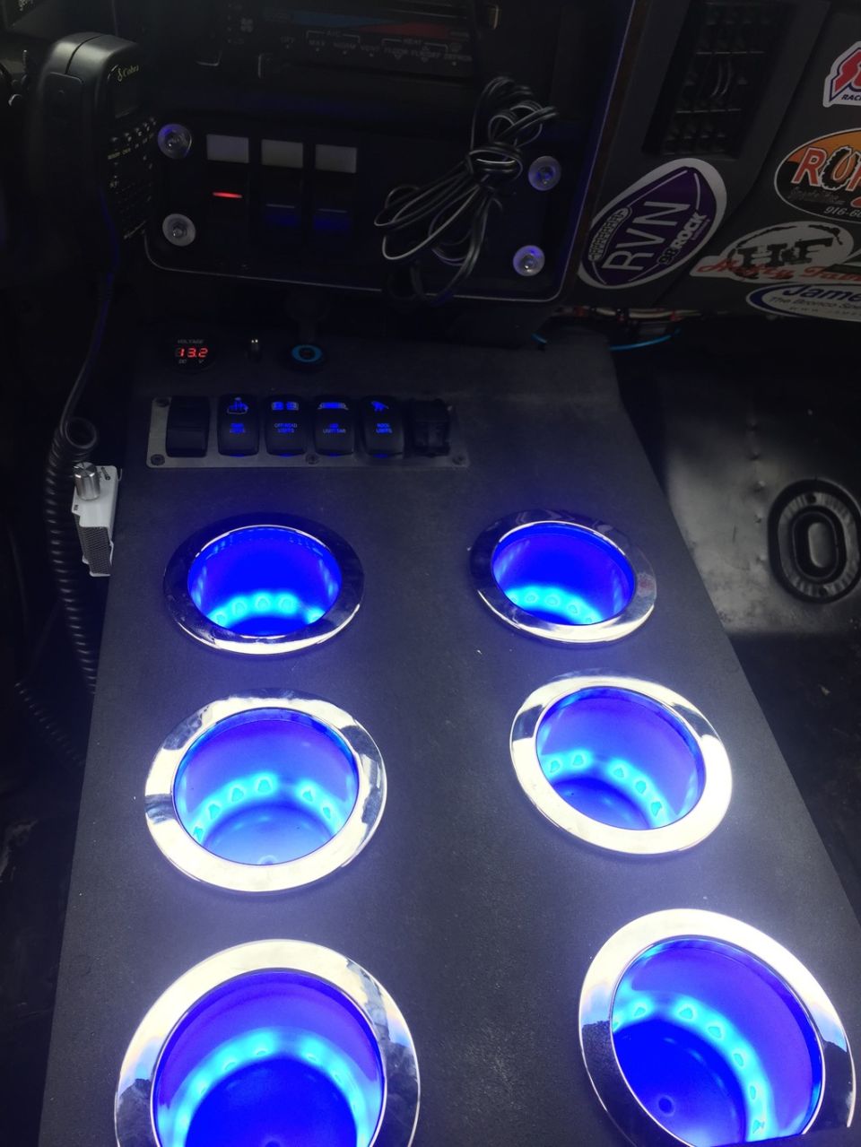 Vehicle interior console with six illuminated blue cup holders and multiple toggle switches