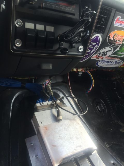 1989 Ford Bronco - The dashboard and floor of a vehicle are shown with exposed wiring and aftermarket electronic components.