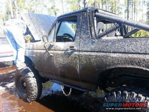 1989 Ford Bronco - This heavily modified SUV, likely a Ford Bronco from the late 1980s, is covered in mud after off-roading.