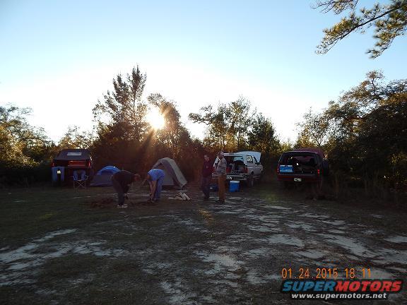 Campsite scene with two SUVs and tents under a bright sun